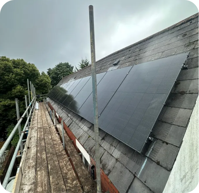Black solar panels on a damp slate roof under a grey sky