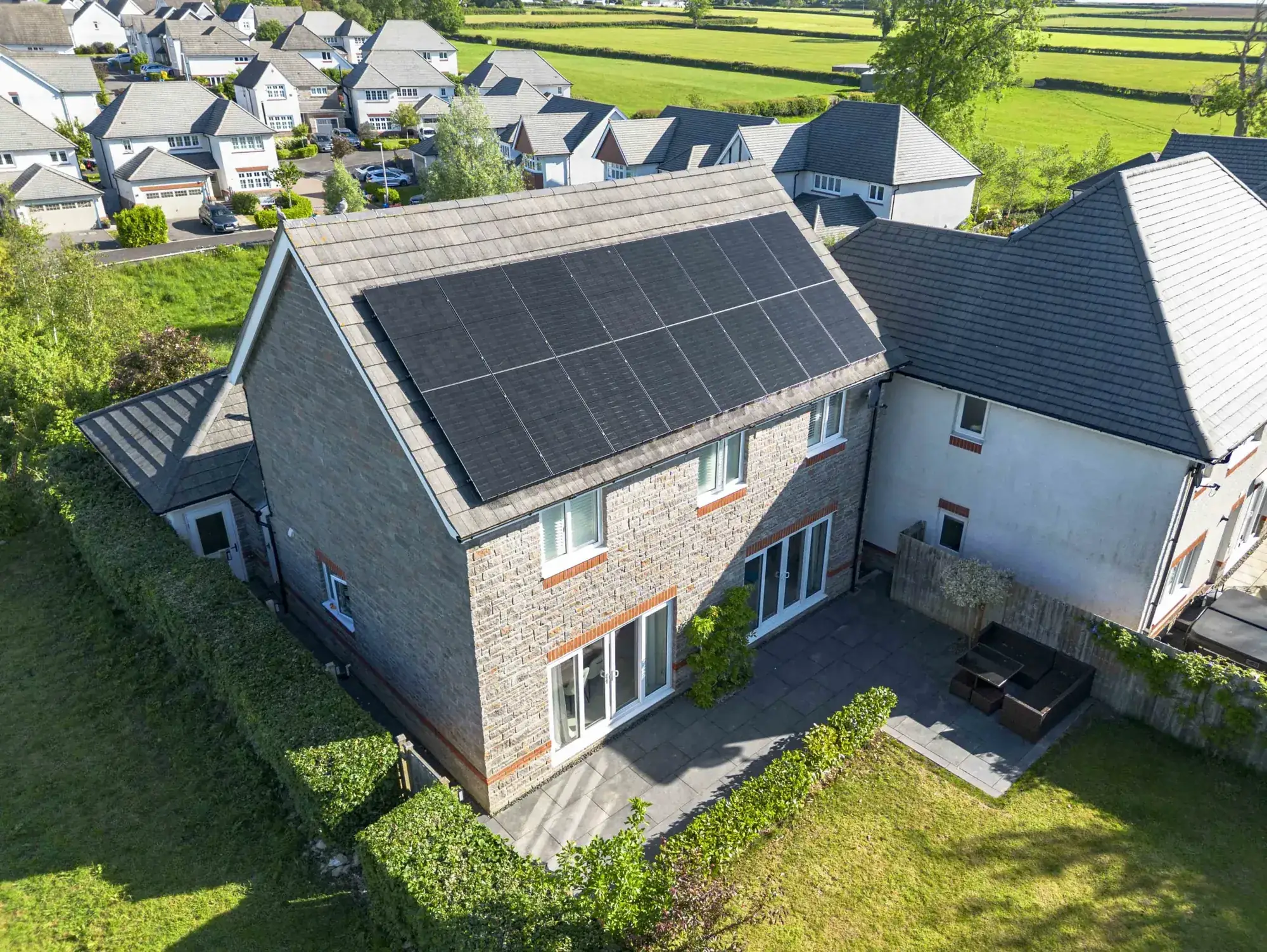 A house with black solar panels on its roof, seen from the air