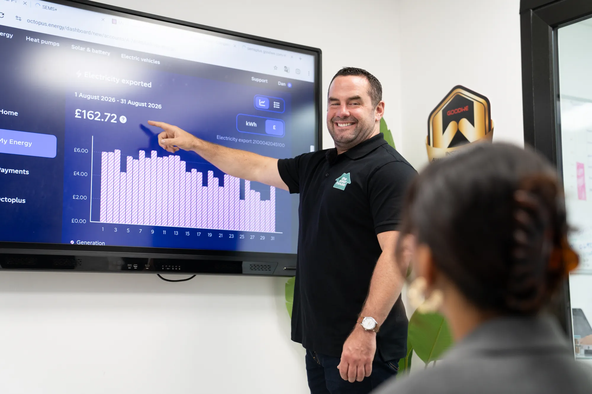 One of our team pointing at a customer's monthly saving on the showroom screen