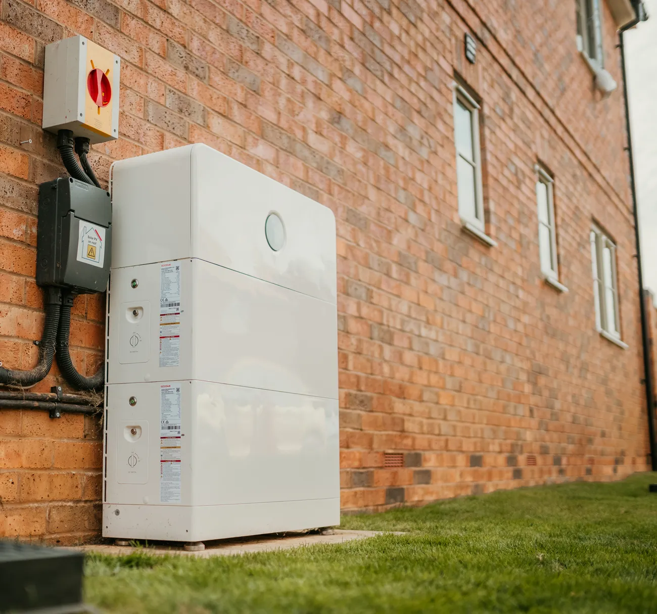 A GoodWe home battery fitted to the outside wall of a brick house