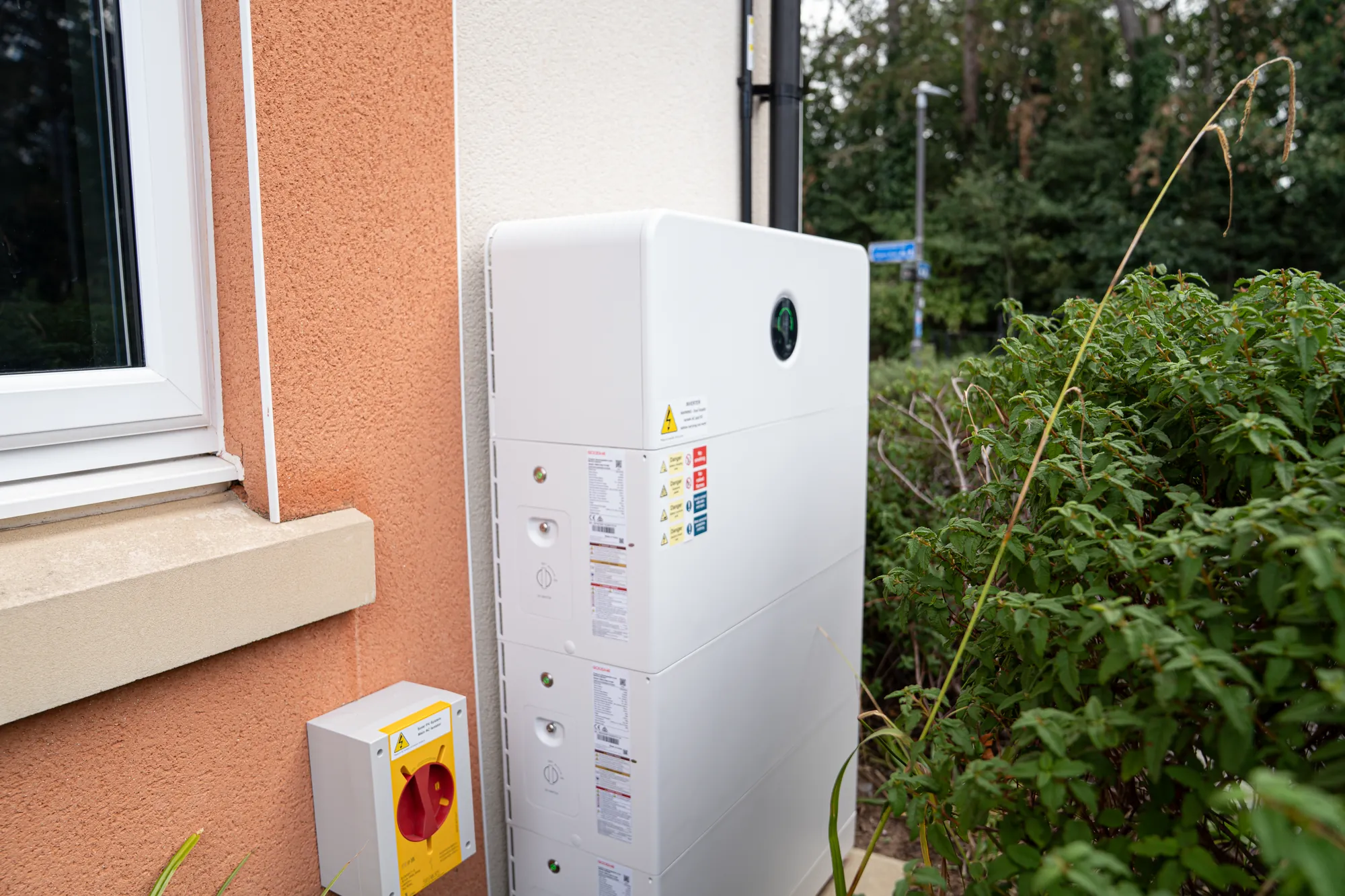 The GoodWe battery stack on the side wall of the house