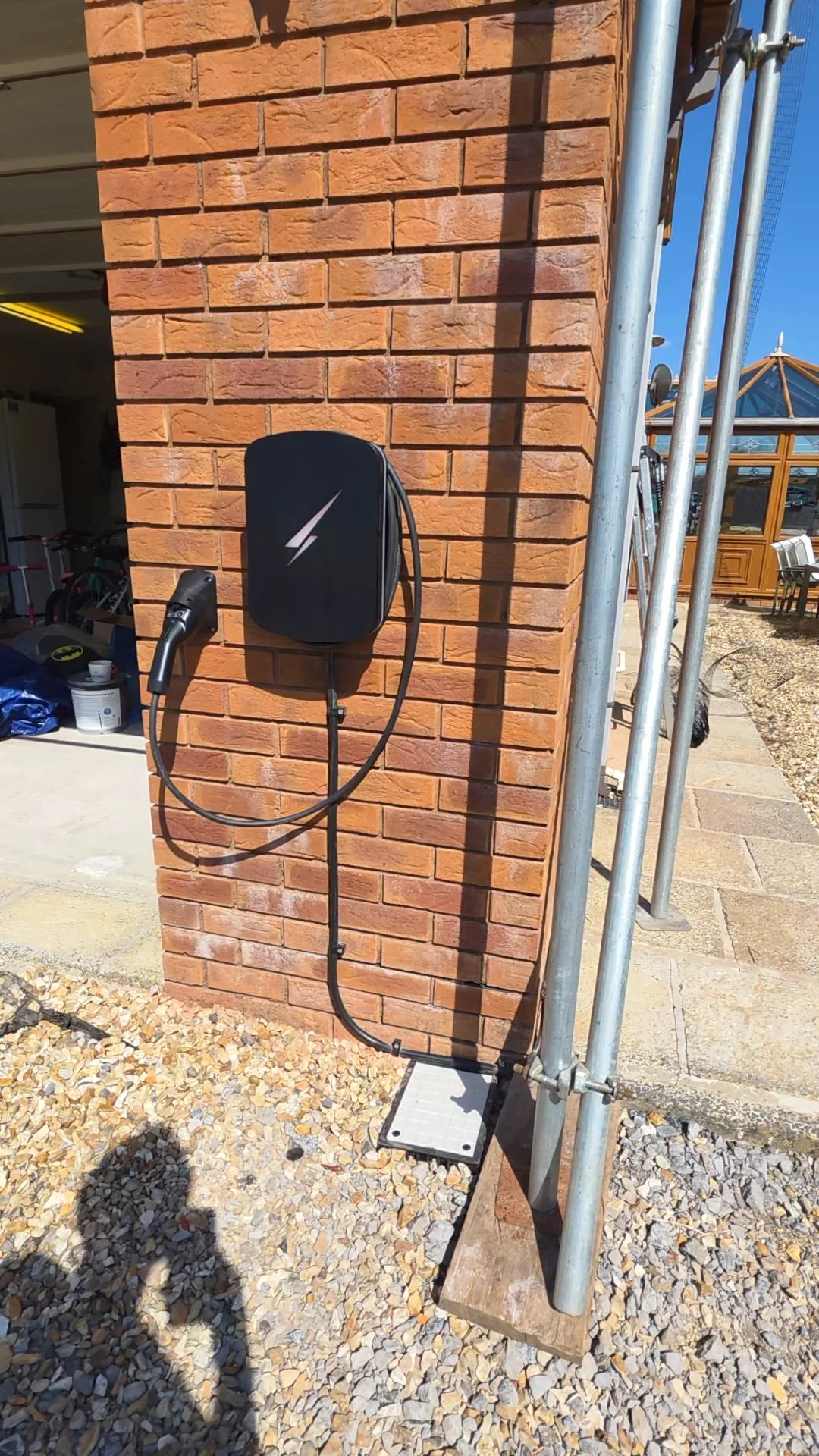 The EV charger fitted on the side wall of the house