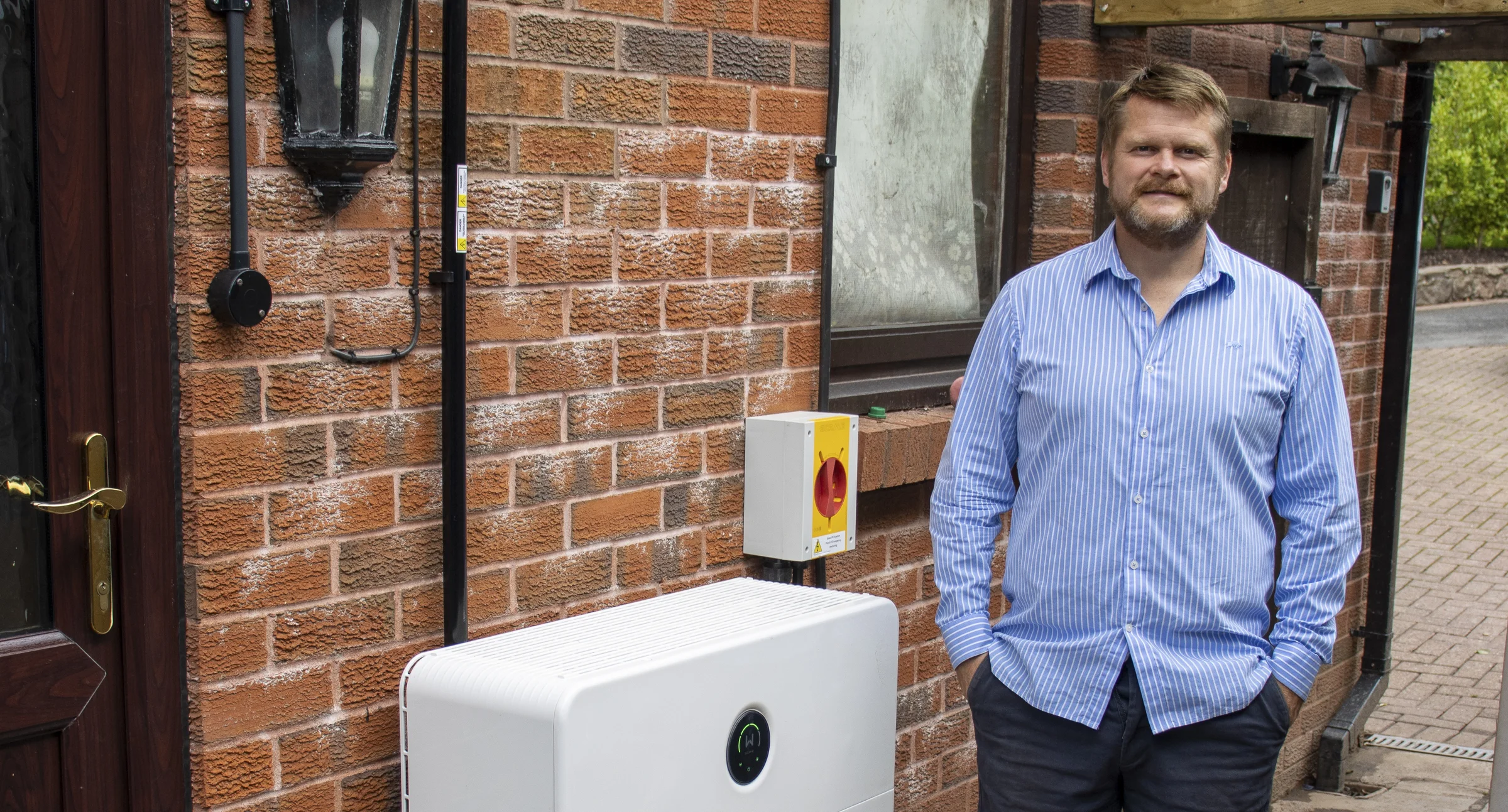 Rob beside his GoodWe inverter and batteries on the outside wall of his North Cardiff home