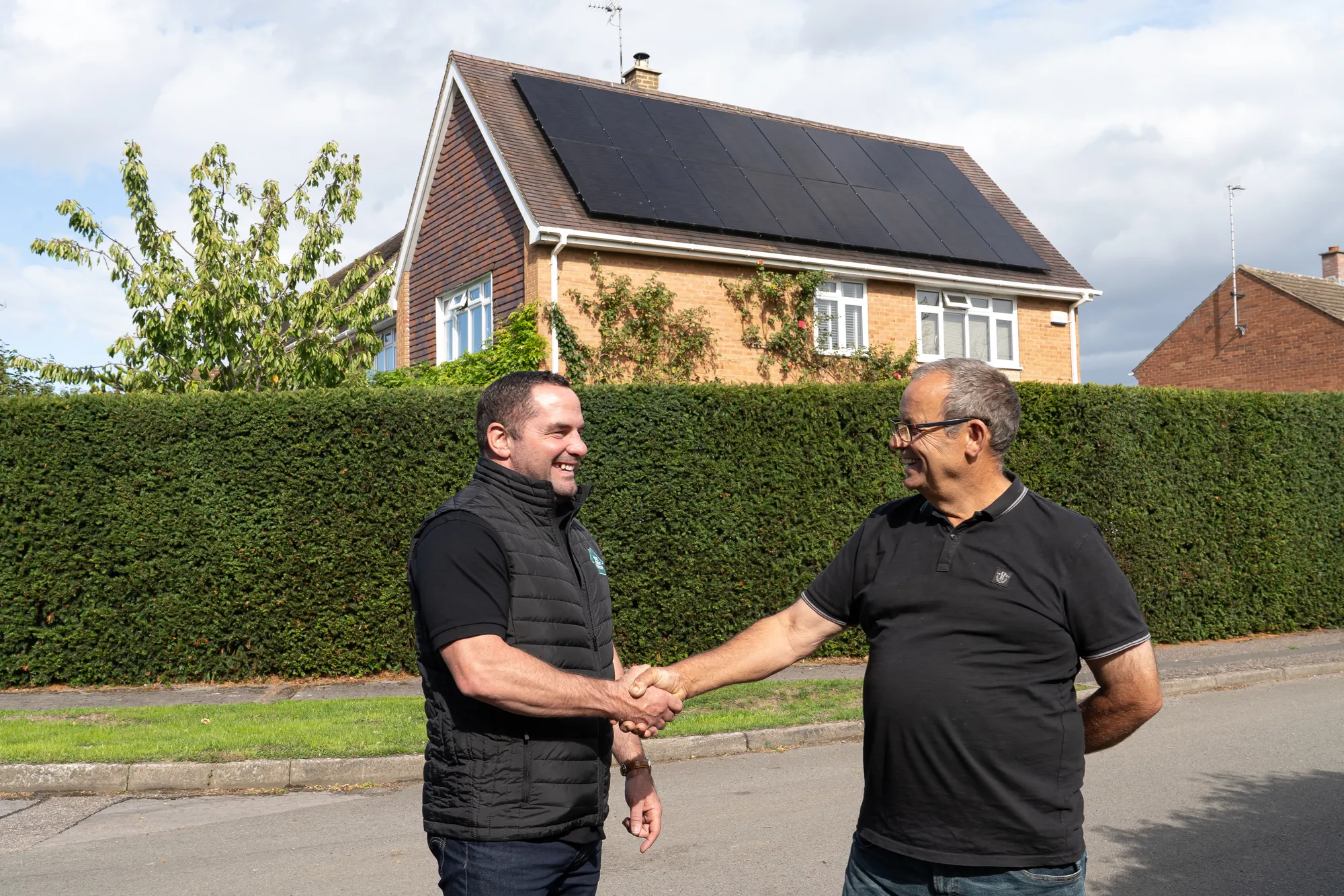 A Solar House adviser shaking hands with a homeowner outside his home in Staverton, Cheltenham