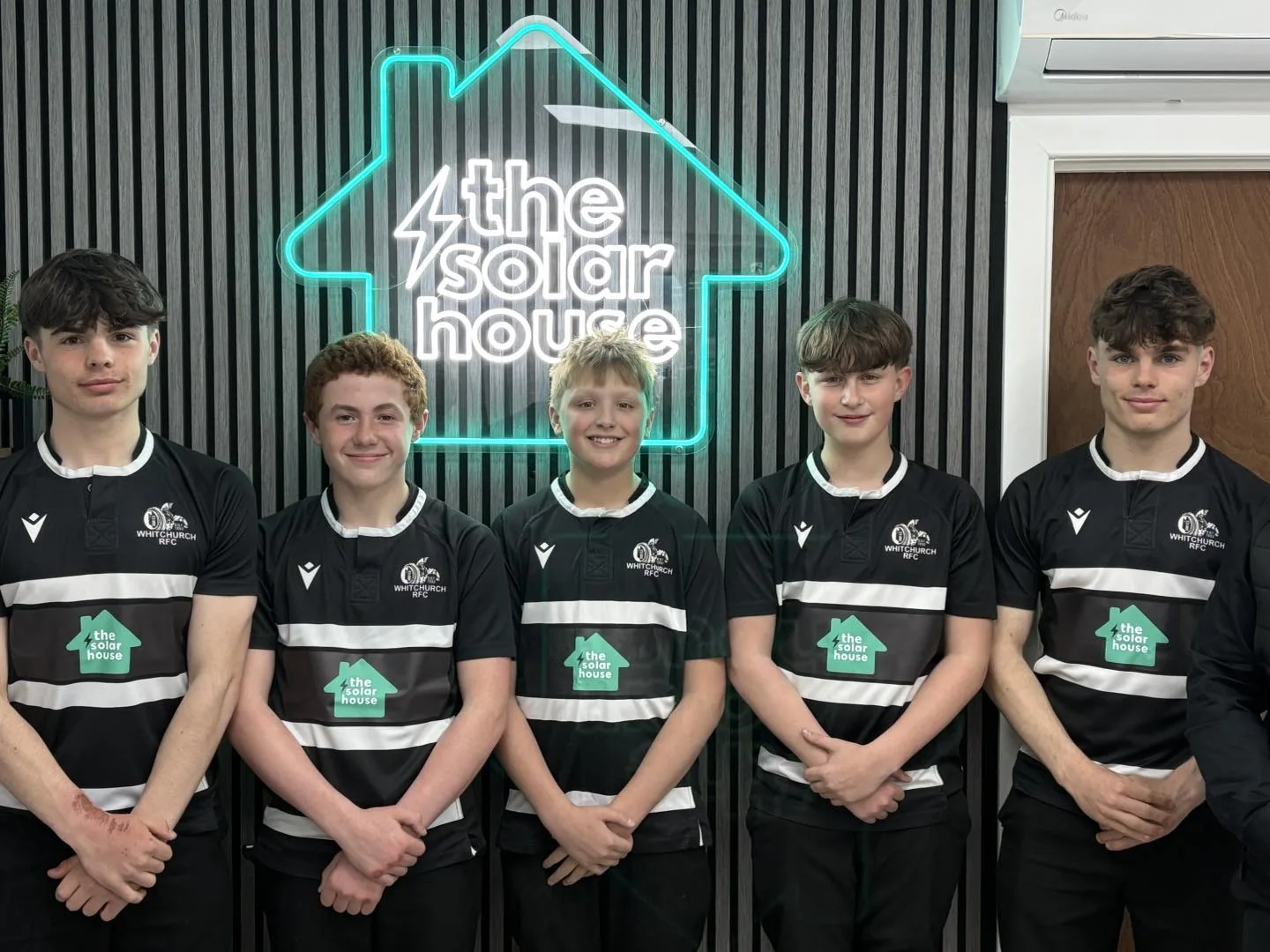 Whitchurch RFC under-14s, a team we sponsor, in front of The Solar House neon logo