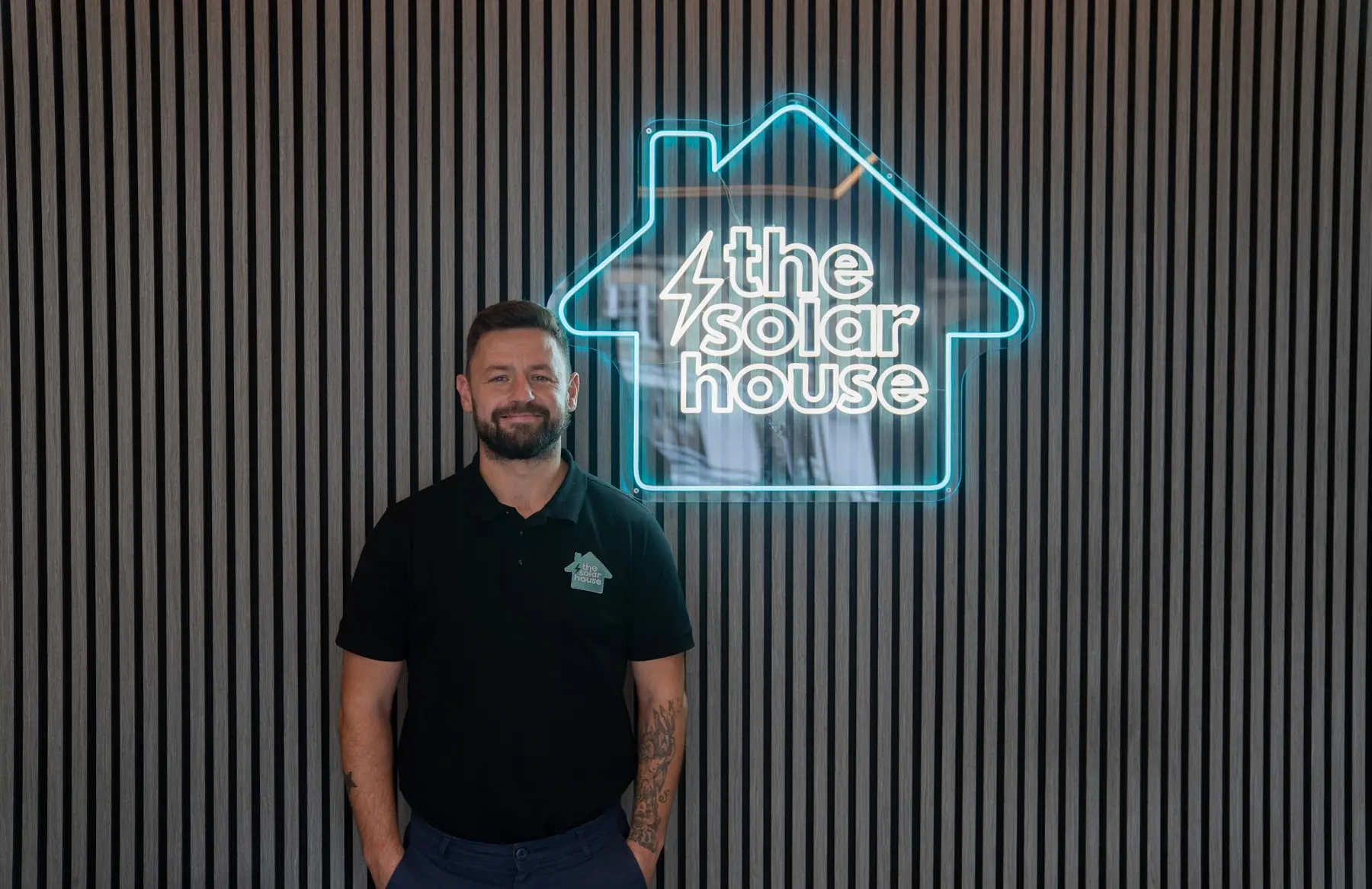 Jason from The Solar House by the neon logo in our showroom