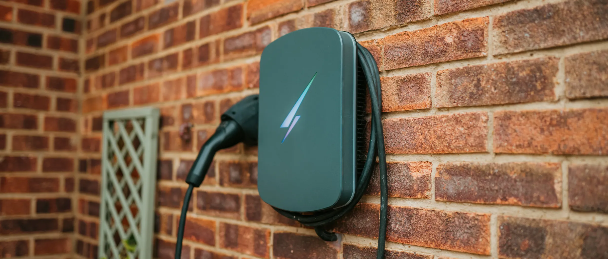 A home EV charger fitted on a brick wall