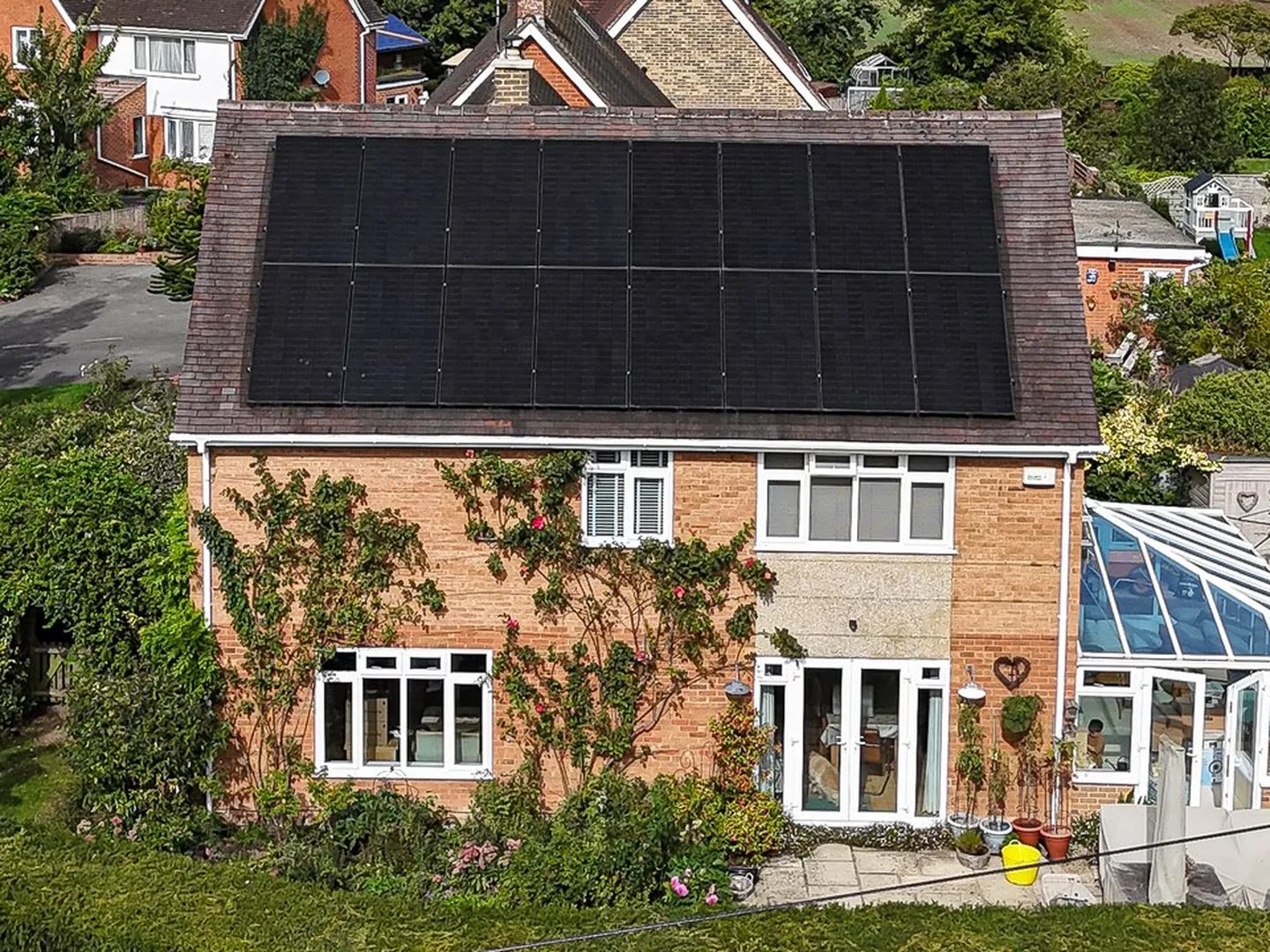 A detached home in Staverton with black solar panels on the roof, seen from the air